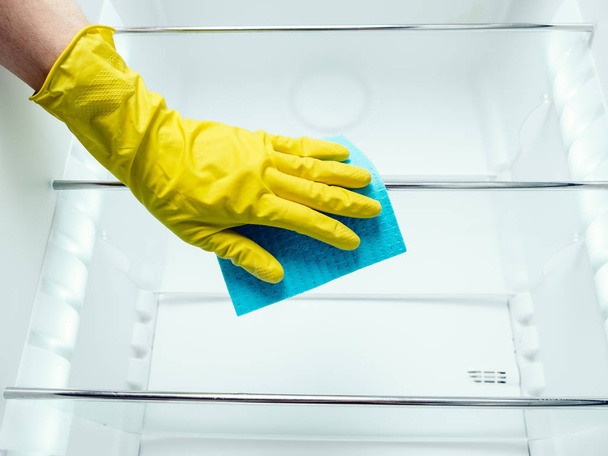 Man's hand cleaning white fridge with blue rag - Foto, imagen