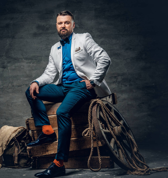 Bearded male sits on a wooden box - Photo, Image
