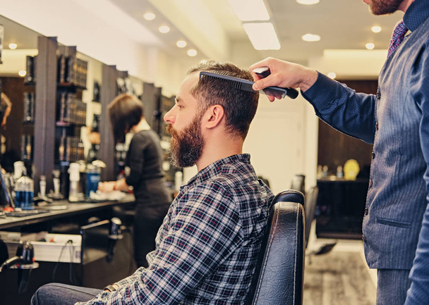 Stylish male hairdresser doing haircut  - Fotó, kép