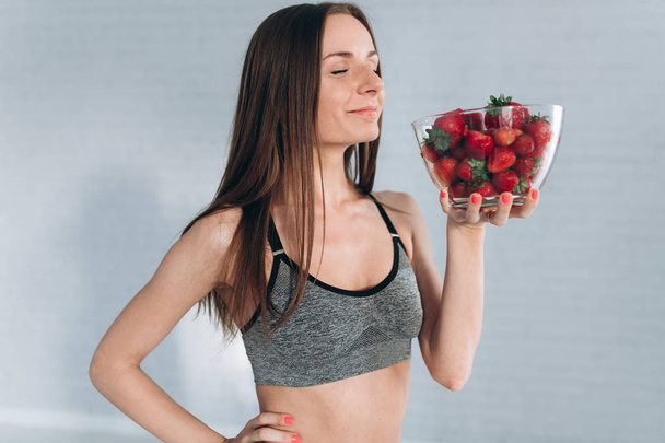 Chica de fitness sosteniendo fresas
 - Foto, Imagen