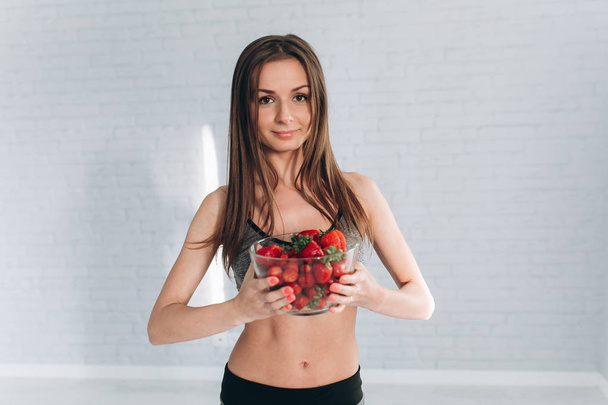 Fitness meisje bedrijf aardbeien - Foto, afbeelding