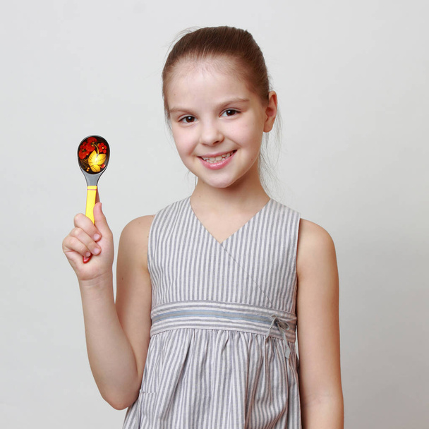Beautiful european little girl holding Art spoon in russian Hohloma style - Φωτογραφία, εικόνα