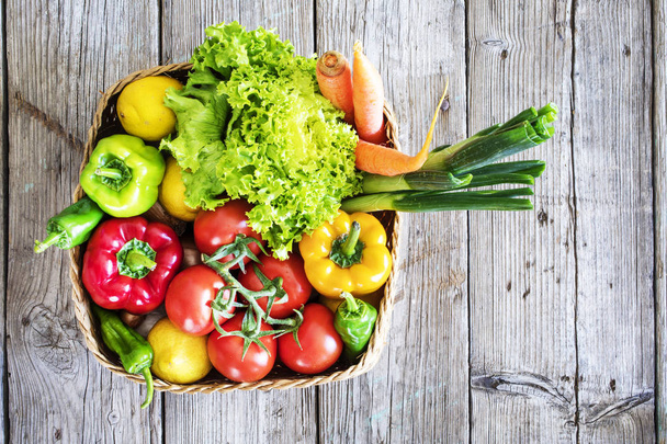 Vegetables in basket on wooden table - Фото, зображення