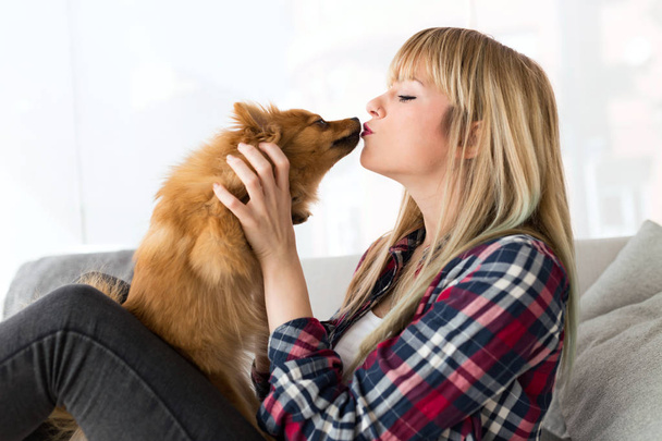 Beautiful young woman with dog playing at home. - Foto, Bild