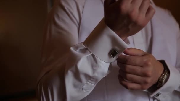 新郎は結婚式のスーツ、ネクタイに手を繋いでください。クローズ アップ手マンの方法を着ている白シャツ、カフスボタン。ビジネスの男性は白いシャツに黒のネクタイを固定します。新郎の結婚式の日の修正にネクタイ、ヴィンテージ - 映像、動画