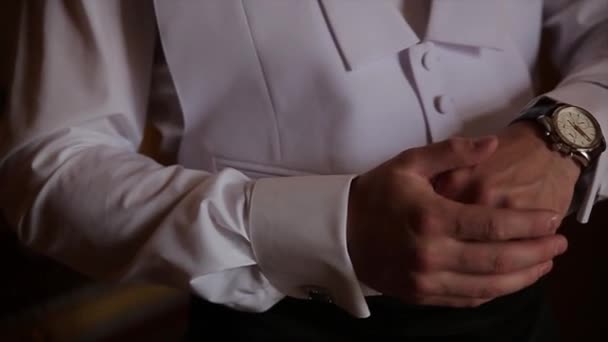 Жених держит за руки галстук, свадебный костюм. Закрыть руки человек, как носит белую рубашку и запонку. Деловой человек чинит черный галстук на белой рубашке. Жених в день свадьбы чинит галстук, винтаж
 - Кадры, видео