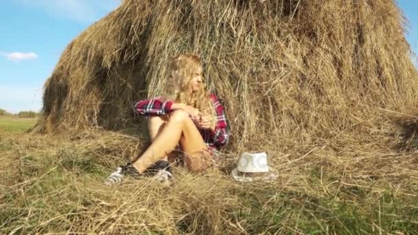 молодая женщина отдыхает возле стога сена
  - Кадры, видео