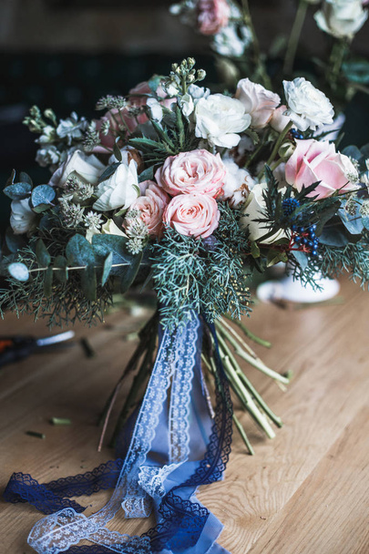Florist workplace: flowers and accessories on a vintage wooden table. soft focus. Modern bouquet in a vase on a table, simple composition - 写真・画像