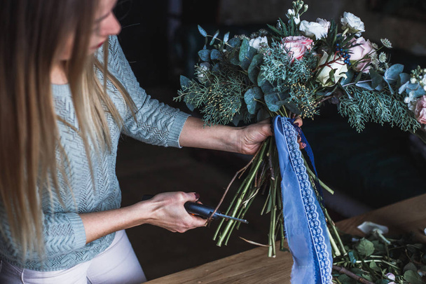 Floristin bei der Arbeit: Hübsche junge blonde Frau hält modernen Blumenstrauß in der Hand - Foto, Bild