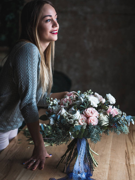 Florist at work: pretty young blond woman holds fashion modern bouquet of different flowers - Foto, imagen