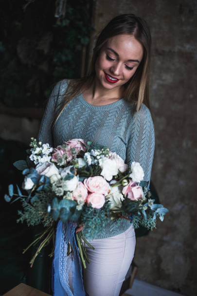 Florist at work: pretty young blond woman holds fashion modern bouquet of different flowers - 写真・画像