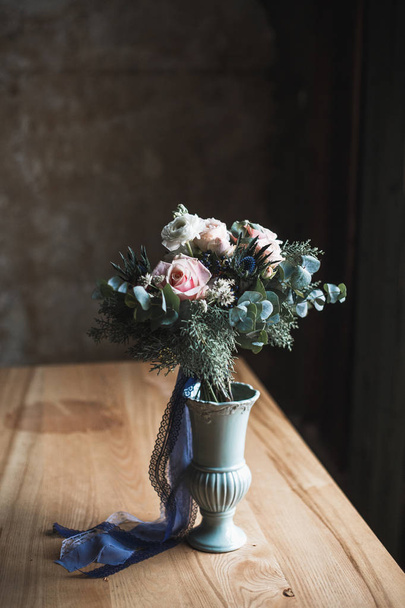 Florist workplace: flowers and accessories on a vintage wooden table. soft focus. Modern bouquet in a vase on a table, simple composition - Foto, imagen