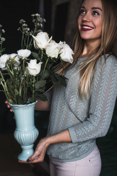 Florist at work: pretty young blond woman holds fashion modern bouquet of different flowers - Photo, image