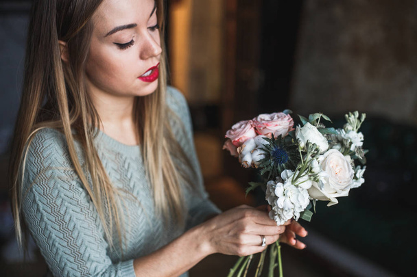 Florist at work: pretty young blond woman holds fashion modern bouquet of different flowers - Foto, immagini