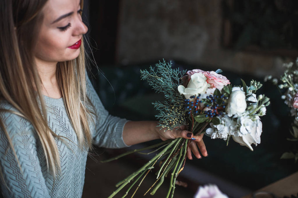 Florist at work: pretty young blond woman holds fashion modern bouquet of different flowers - Foto, afbeelding