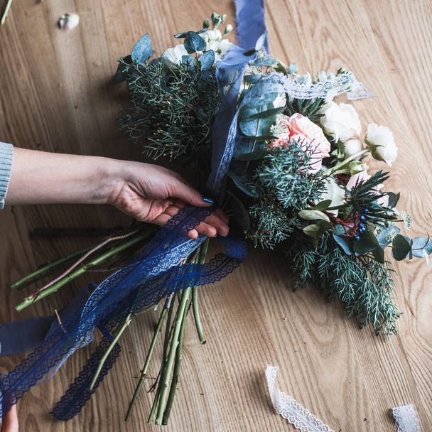 Florist at work: pretty young blond woman holds fashion modern bouquet of different flowers - Foto, afbeelding
