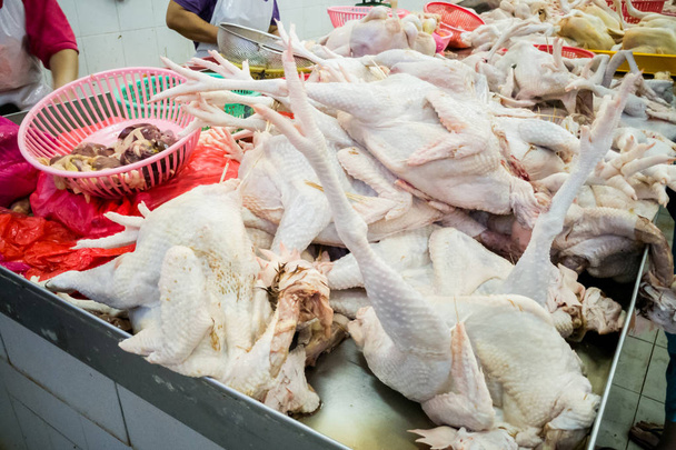 Vendedor que vende frango inteiro recém-abatido na banca do mercado
 - Foto, Imagem
