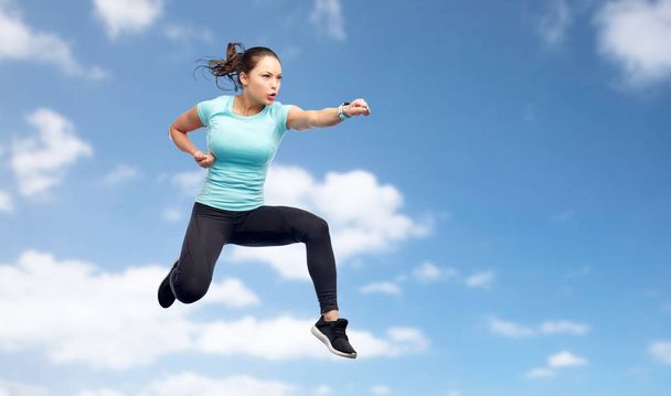 sporty woman jumping in fighting pose over sky - Zdjęcie, obraz