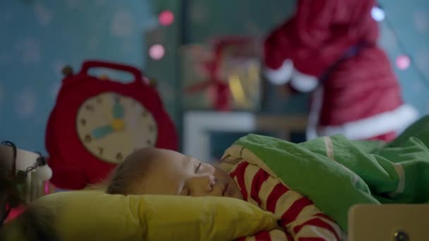 Its midnight on Christmas and Santa Claus is bringing gifts for little boy sleeping in his cot - Кадры, видео