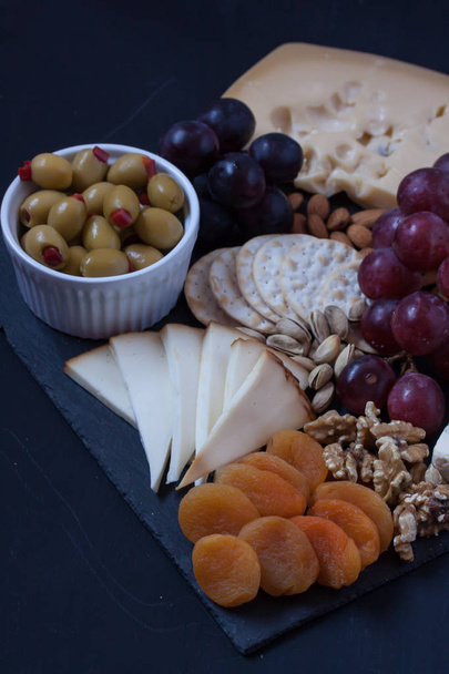 cheese, grape, cracker and olive on a black background - Фото, зображення