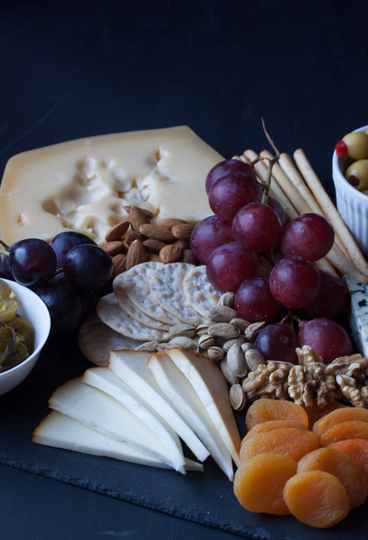 cheese, grape, cracker and olive on a black background - Photo, image