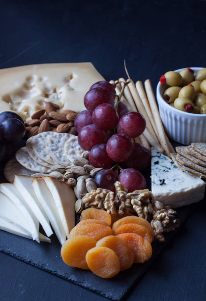 cheese, grape, cracker and olive on a black background - Photo, Image
