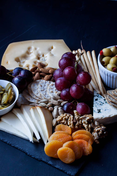 cheese, grape, cracker and olive on a black background - Valokuva, kuva