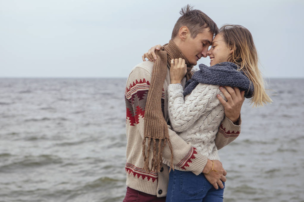 Happy thoughtful couple standing on a rock beach near sea huggin - Photo, Image