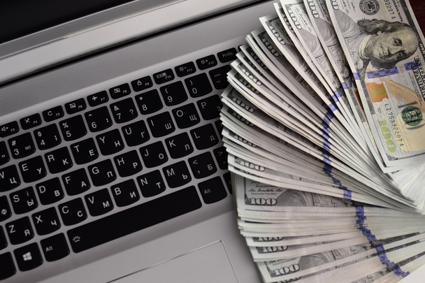 bankbiljetten over laptop toetsenbord - Foto, afbeelding
