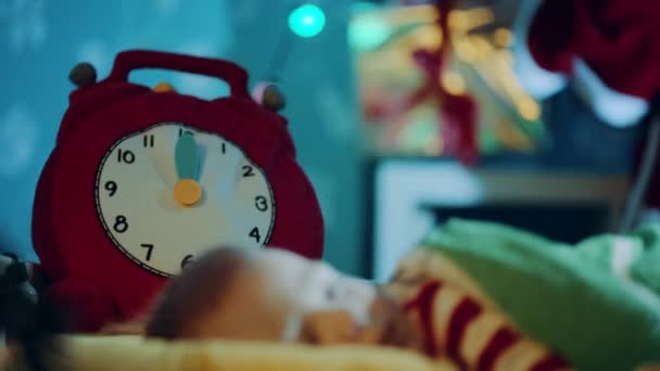 Close up portrait of little pretty boy sleeping in his cot on Christmas night. Toy clock is striking midnight. Christmas present is on the background - Metraje, vídeo