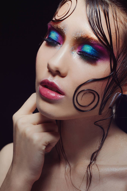 Young beautiful girl bright makeup with a wet look shine, dark background - Valokuva, kuva