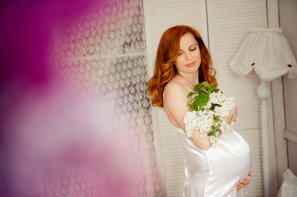 Pregnant woman with red hair in white dress - Fotoğraf, Görsel
