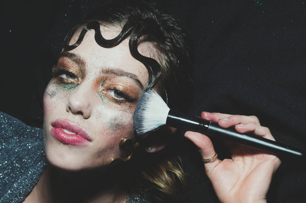 Pretty fashion girl putting holiday glitter makeup - Foto, Imagen