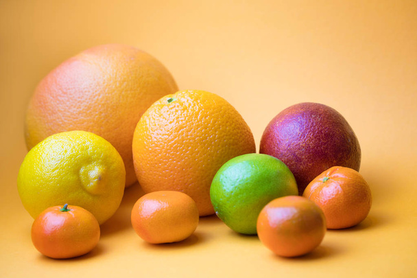 Assorted fresh citrus fruit on a yellow  background - Zdjęcie, obraz