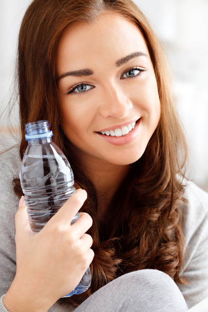 Pretty young girl holding a bottle of water and smiling - Foto, imagen