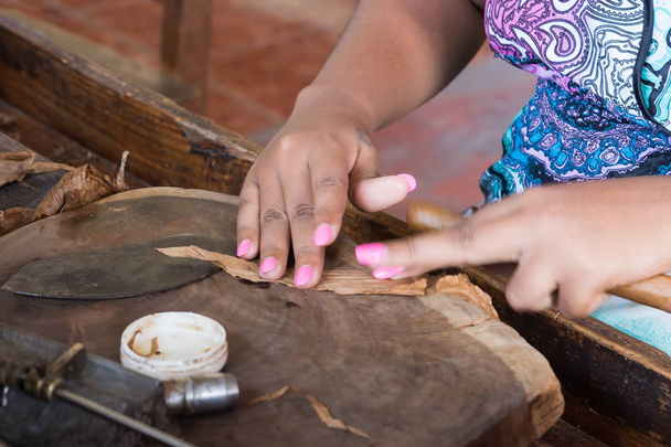Closeup of hands making cigar from tobacco leaves. Traditional manufacture of cigars. Dominican Republic - Photo, Image
