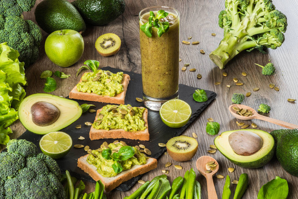 Comida verde saudável. Sanduíches vegan com abacate e legumes no fundo de madeira. Dieta de desintoxicação. Kiwi suco fresco
 - Foto, Imagem