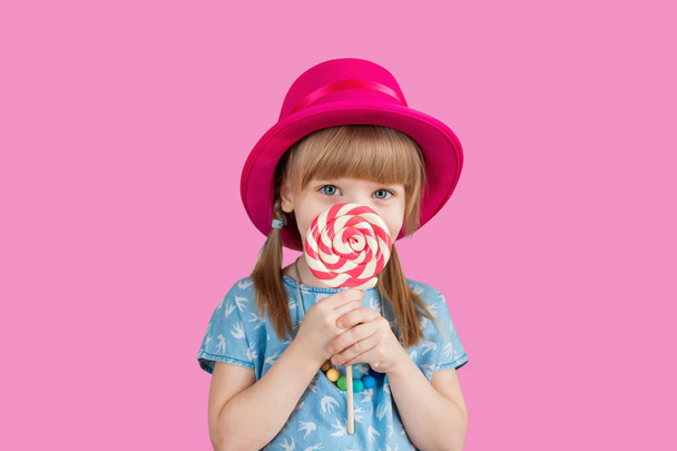 Isolated on bright background, studio. Beautiful little girl with lollipop - 写真・画像