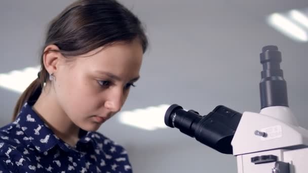 School girl looking into microscope. Close-up. - Filmagem, Vídeo