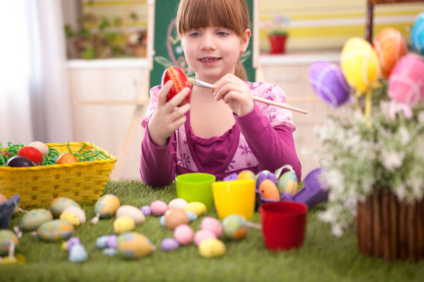  happy smiling young girl painting eggs in home kitchen - Photo, Image