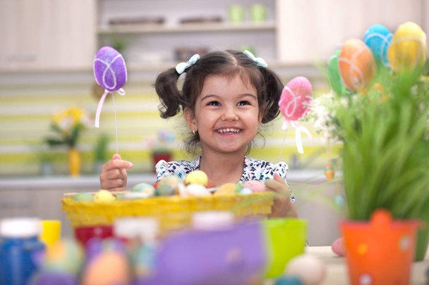 Cute little girl with basket full of colorful easter eggs - Zdjęcie, obraz
