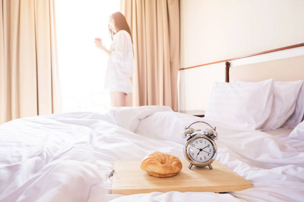 Γυναίκα τεντωμένο στο κρεβάτι μετά το ξυπνητήρι και το ψωμί στο t - Φωτογραφία, εικόνα
