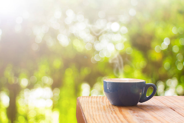 Coffee cup with stream of vapour on wood table against natural b - 写真・画像