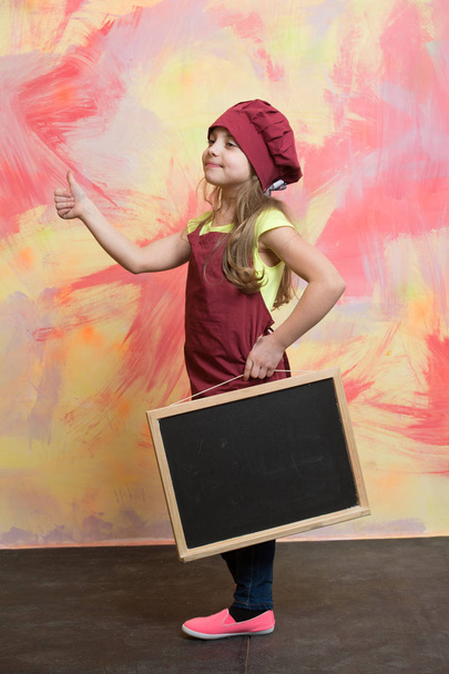 small happy girl chef in hat, apron with blackboard - Фото, изображение