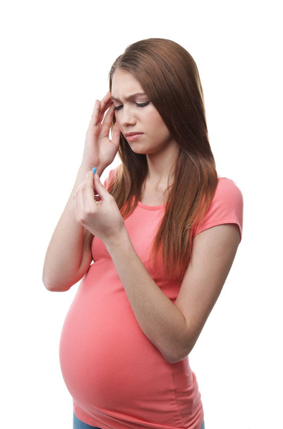 Pregnant woman taking pill against headaches on white background - Foto, Imagen