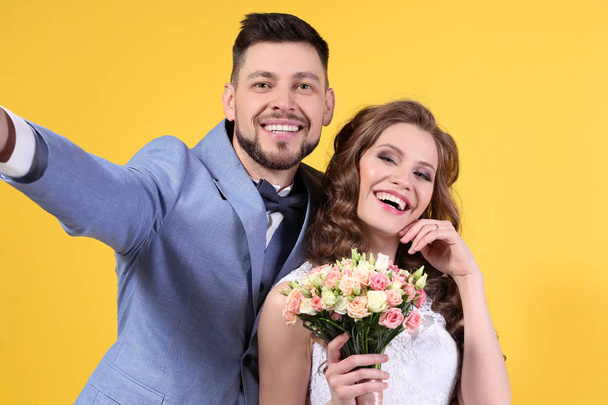 Happy wedding couple making selfie on color background - 写真・画像