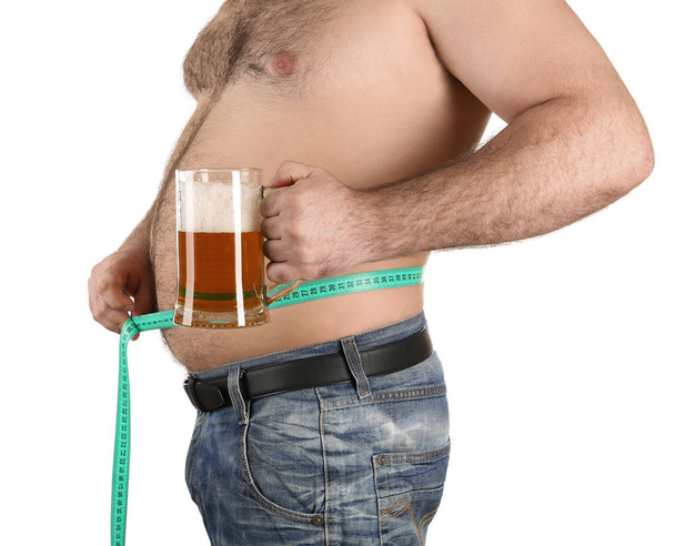 Mann misst Bauch und hält Glas Bier in der Hand  - Foto, Bild