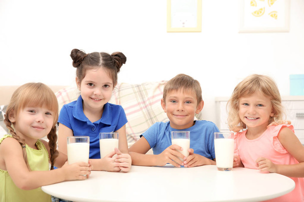 Happy children with glasses of milk at table - Foto, immagini