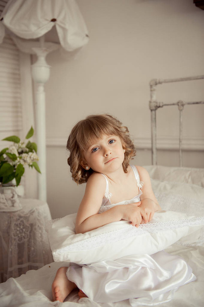 The little girl woke up in the morning and sits on the bed - Foto, immagini