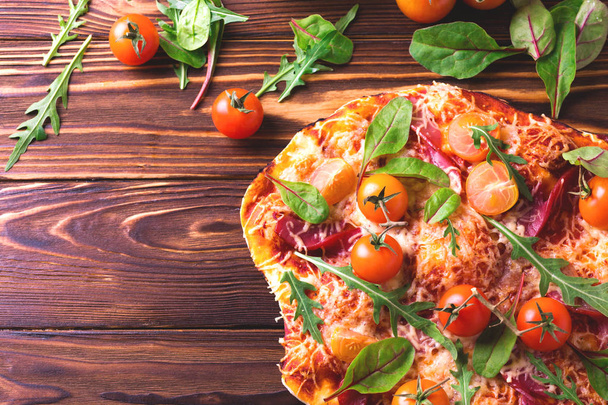 Homemade pizza with bacon, tomatoes, spinach, arugula and cheese - Foto, afbeelding